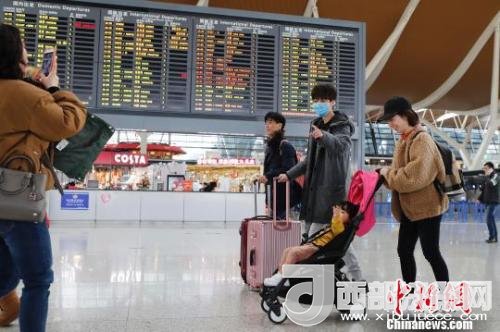 旅客帶著孩子前往辦票柜臺(tái)辦理登機(jī)手續(xù)?！∫罅⑶?攝