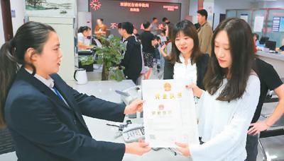 河北省承德市網絡代購經營者陳晨(右)從工作人員手中接過帶有統一社會信用代碼的營業(yè)執(zhí)照。 劉環(huán)宇攝(人民圖片)